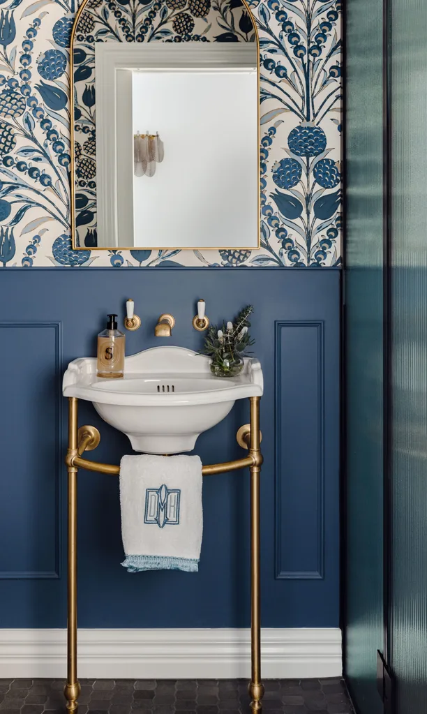 Blue powder room with wallpaper.