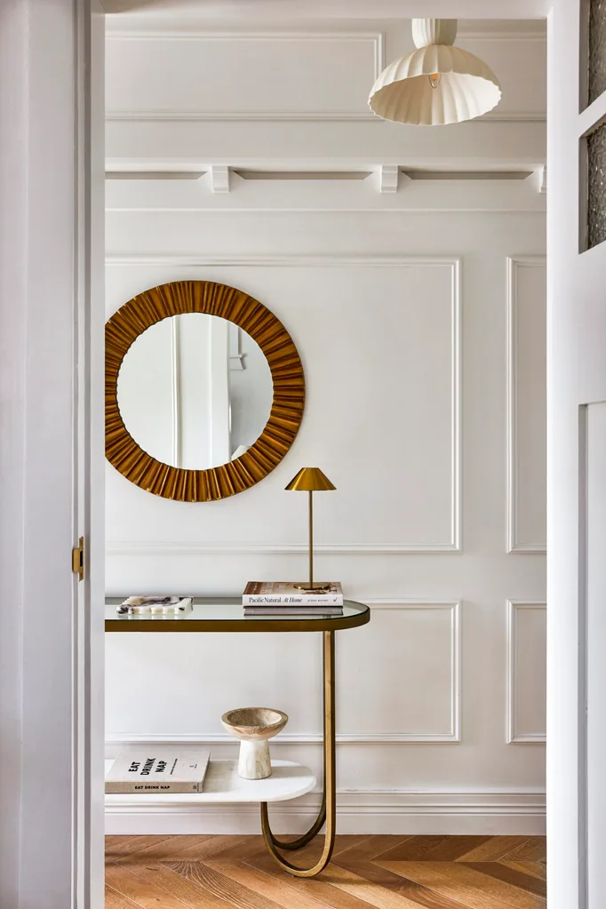 Californian bungalow renovation hallway with chevron oak floors, a round mirror, brass console and wainscoting