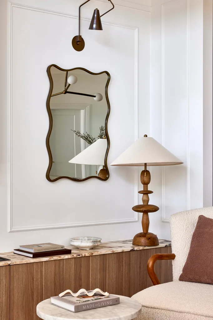 Californian bungalow renovation neutral living room with a wavy mirror, marble benchtop, table lamp and wainscoting