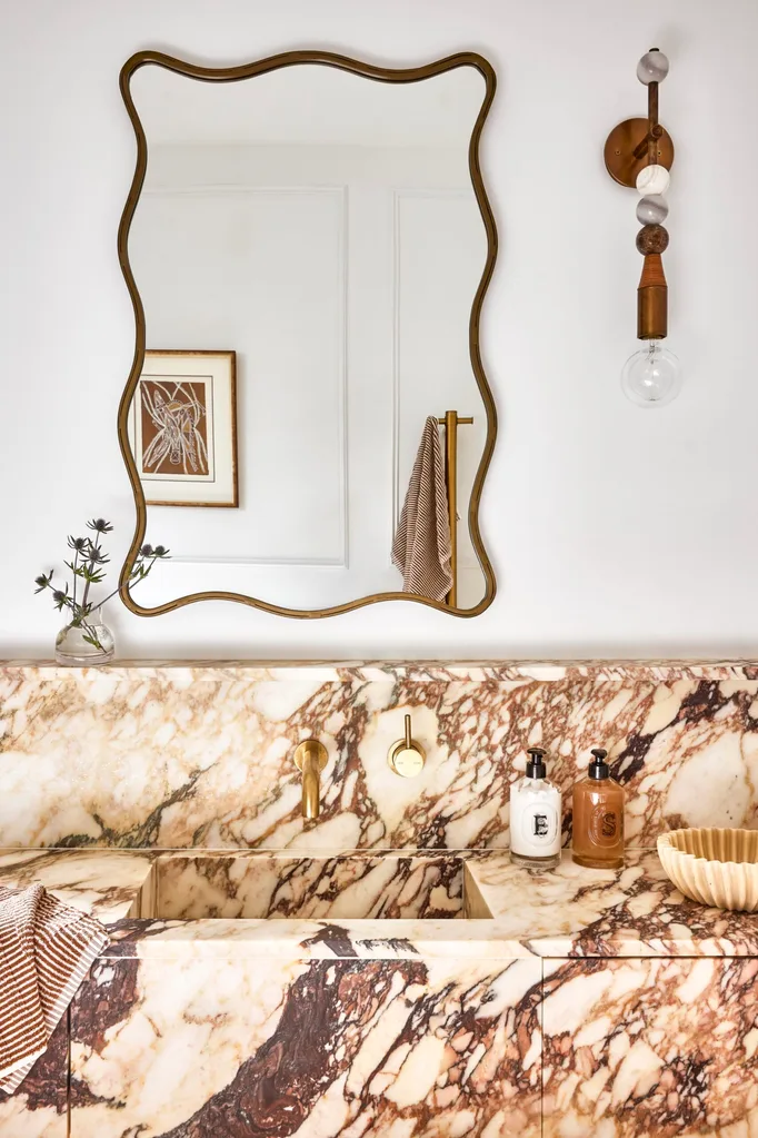 Californian bungalow renovation main bathroom with marble vanity and wavy mirror and light sconce plus brass tapware