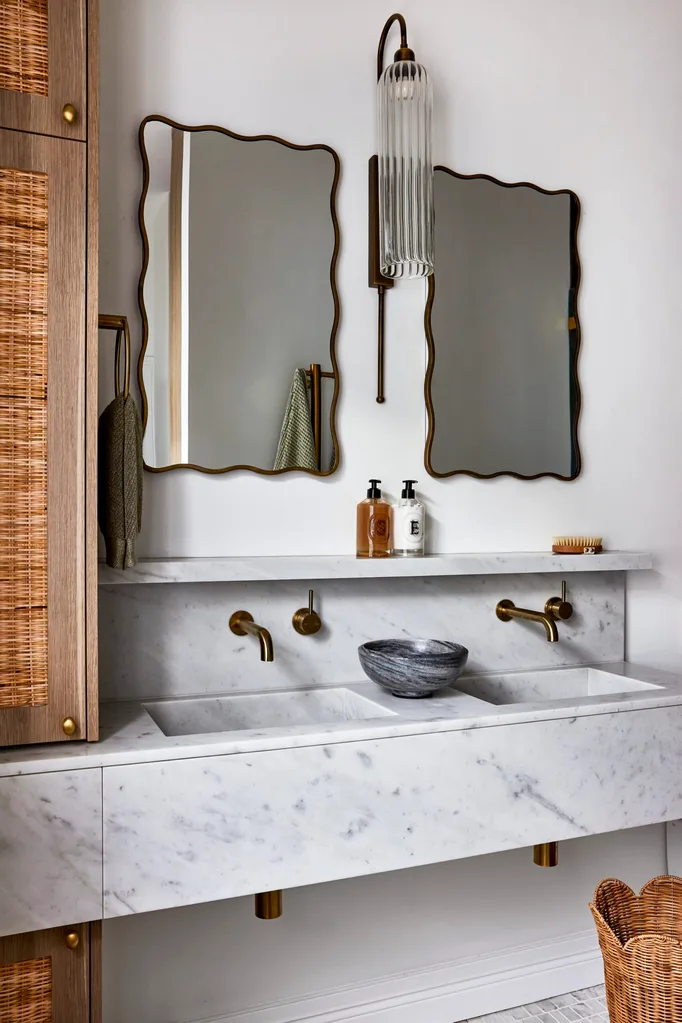 Californian bungalow renovation main ensuite bathroom with a marble vanity, brass tapware, wavy mirror and rattan cabinet
