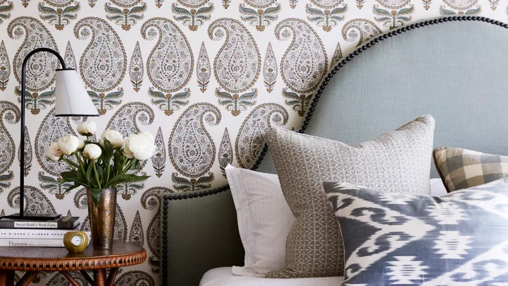 Main bedroom with upholstered pale blue bedhead and paisley wallpaper