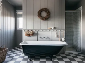 Elegant bathroom with a black clawfoot tub, gray walls, checkered floor, woven wreath, and glass shower.