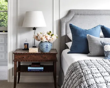 A country style bedroom with wainscoting and vintage-style furniture.